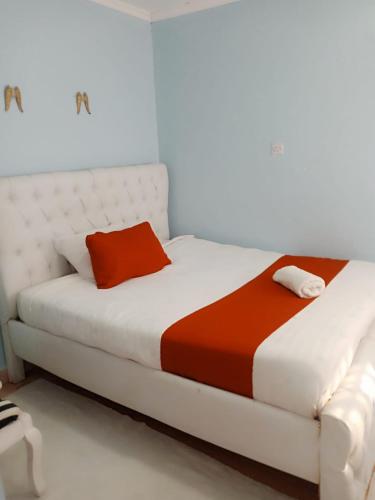 a white bed with an orange and white blanket at Runda UN Gigiri - kikao private cottage in Nairobi