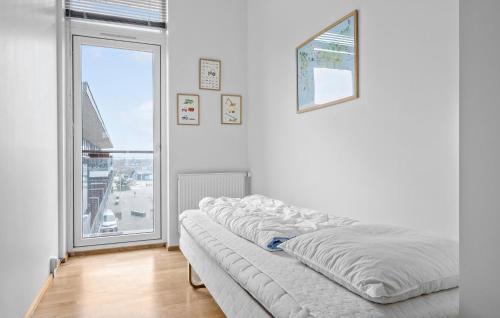 Cama en habitación blanca con ventana grande en 3 Bedroom Stunning Apartment In Rm en Havneby