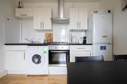 een keuken met witte kasten en een wasmachine en droger bij Cosy Leith Escape - Edinburgh City in Edinburgh