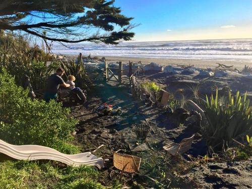 a man and a child sitting on the beach at Kahu's Nest in Hokitika