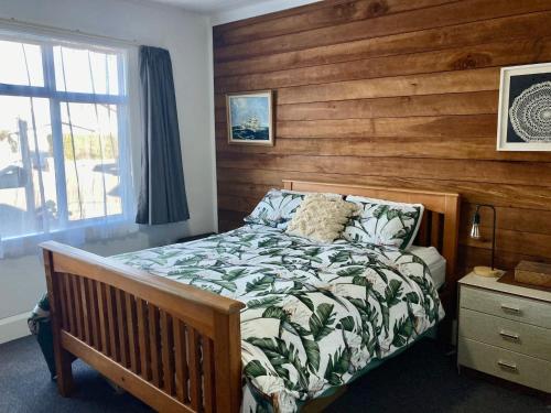 a bedroom with a bed with a wooden wall at Kahu's Nest in Hokitika