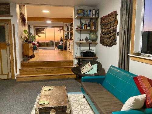 a living room with a blue couch and a table at Kahu's Nest in Hokitika