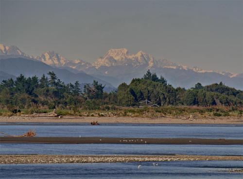a large body of water with mountains in the background at Kahu's Nest in Hokitika
