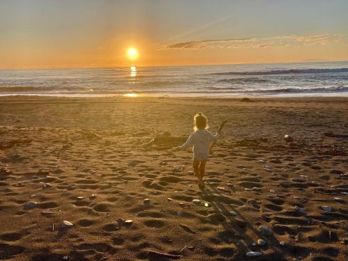 a woman walking on the beach at sunset at Kahu's Nest in Hokitika