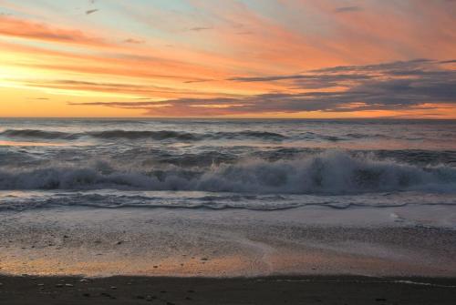 a sunset on the beach with the ocean at Kahu's Nest in Hokitika