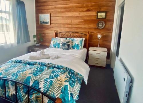a bedroom with a bed with a wooden wall at Kahu's Nest in Hokitika