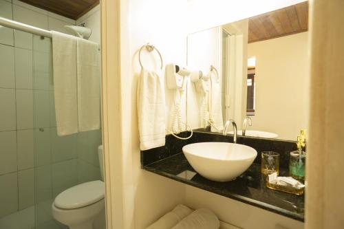 a bathroom with a sink and a toilet and a mirror at Regina Apartments in Morro de São Paulo