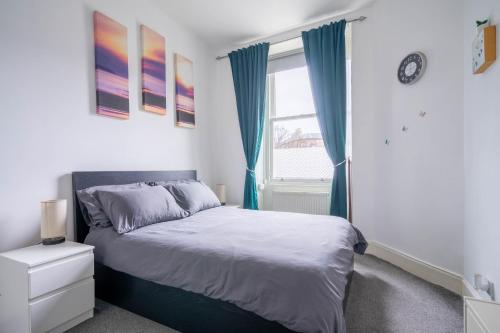 een slaapkamer met een bed met blauwe gordijnen en een raam bij Cosy Leith Escape - Edinburgh City in Edinburgh
