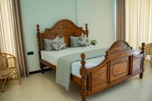 a bedroom with a wooden bed with pillows at Madushan Garden & Villa in Weligama