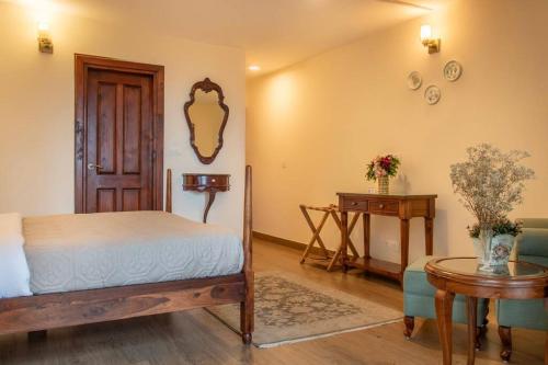 a bedroom with a bed and a table and a mirror at Jais Cottage A Charming Hideaway in Shimla