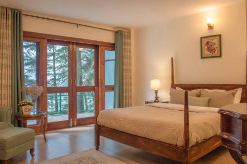 a bedroom with a bed and a large window at Jais Cottage A Charming Hideaway in Shimla