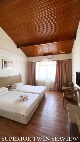 1 dormitorio con 2 camas y techo de madera en Lovita Tanjung Bidara Beach Resort en Melaka