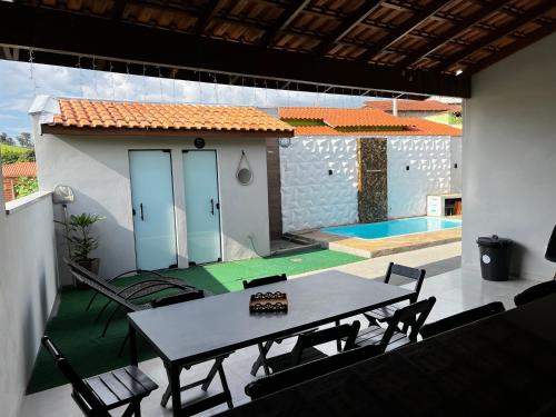 eine Terrasse mit einem Tisch, Stühlen und einem Pool in der Unterkunft Chacara em Socorro- SP próx ao centro, com piscina e area gourmet in Socorro