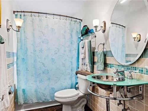 ein Badezimmer mit Toilette, Waschbecken und Spiegel in der Unterkunft 7 Palms Pool House in Cape Coral