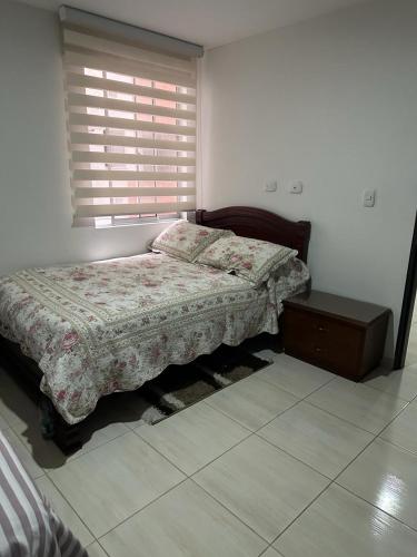 a bedroom with a bed and a nightstand and a window at Aparta estudió independiente cerca a la concha acústica (central) in Ibagué