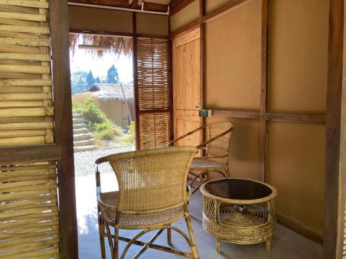 two wicker chairs and a table on a porch at Art Mile Kalimpong in Kalimpong