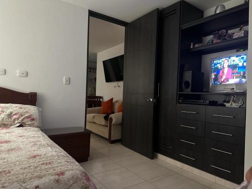 a bedroom with a bed and a flat screen tv at Aparta estudió independiente cerca a la concha acústica (central) in Ibagué