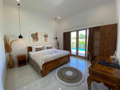 a bedroom with a bed and a desk and a window at The Jangkar Canggu Guesthouse & Villa in Canggu