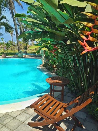 uma cadeira e uma mesa ao lado de uma piscina em Villa Santa Maria Bali em Ambat