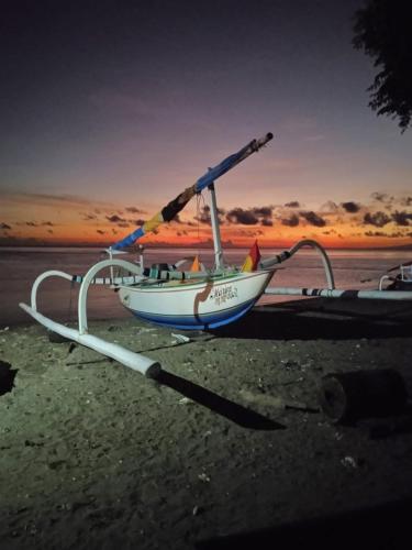um barco na praia com o pôr do sol ao fundo em Villa Santa Maria Bali em Ambat