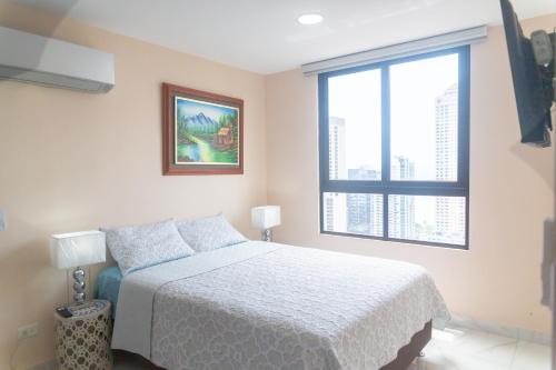 una camera con un letto bianco e una finestra di Apartamento en Panamá Céntrico y lujoso en Panamá de la zona Bancaria a Città di Panama