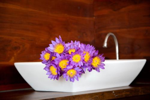 a white bowl with purple and yellow flowers in it at Negombo Green Palace in Negombo