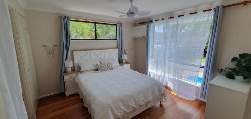 a bedroom with a bed and a large window at Gold Coast Family Retreat, beach 1 and half kms, shops, full home in Gold Coast