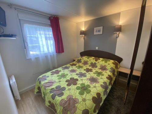 une petite chambre avec un lit avec une couette à fleurs dans l'établissement Mobile Home tout confort 4 pers, proche plage et centre, clim, TV, terrasse, parking - FR-1-709-75, à Fouras