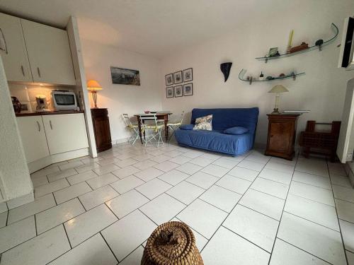 un salon avec un canapé bleu et une table dans l'établissement Appartement Royan avec Terrasse en Bord de Mer - FR-1-494-172, à Royan