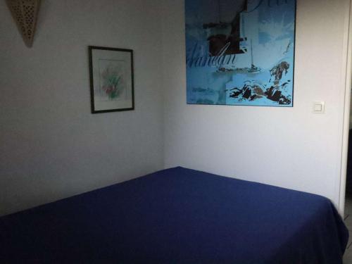 - une chambre avec un lit bleu et une photo sur le mur dans l'établissement Appartement Royan avec Terrasse en Bord de Mer - FR-1-494-172, à Royan