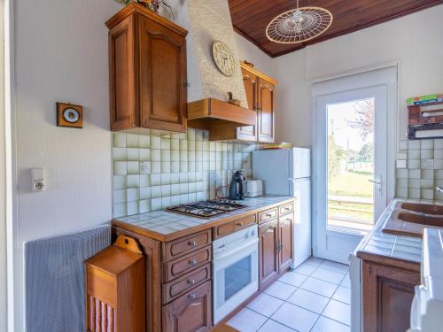 une cuisine avec des armoires en bois et un réfrigérateur blanc dans l'établissement Maison 3 chambres proche plages avec jardin clos à Mimizan - pour 8 personnes - FR-1-50-127, à Mimizan