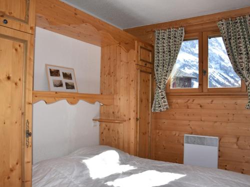 une chambre avec un lit dans une cabane en bois dans l'établissement Charmant 3 pièces avec terrasse proche pistes et centre - FR-1-464-228, à Pralognan-la-Vanoise