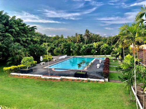 a swimming pool in a yard with trees in the background at Green Island Nature lodge and Villa in Kammala South