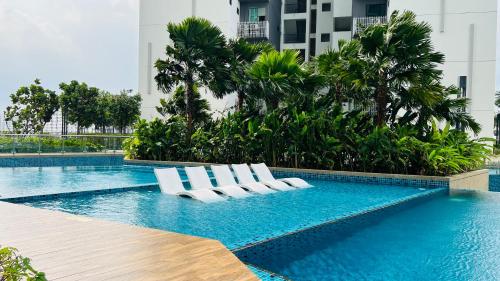 een zwembad met witte ligstoelen in een gebouw bij Sunway Greenfield Residence 3R2B w/Netflix in Petaling Jaya