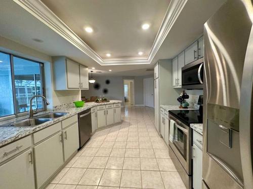 a large kitchen with white cabinets and a large window at Villa Palaco in Cape Coral