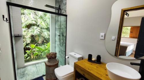 a bathroom with a toilet and a sink and a mirror at Suíte Arara Guest House na Roça - Vila São Francisco in Piracaia