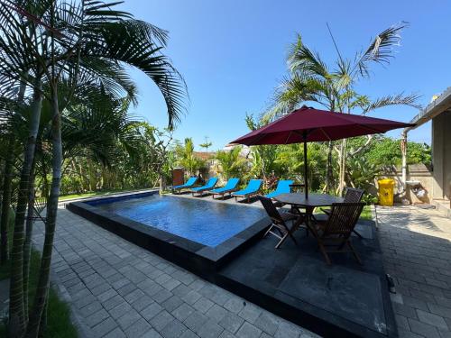 a pool with chairs and a table with an umbrella at Canggu Nadi 2 Guest House in Canggu