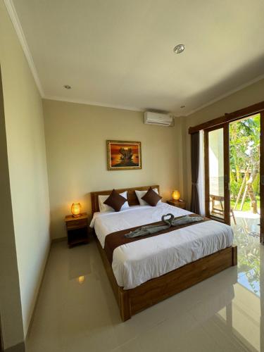 a bedroom with a large bed and a window at Canggu Nadi 2 Guest House in Canggu