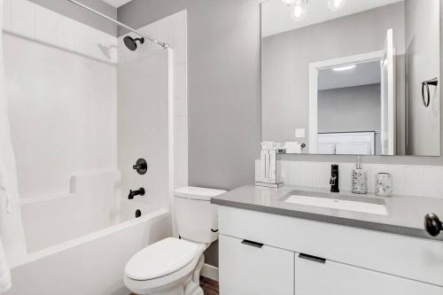 a white bathroom with a toilet and a sink at Brand New Modern Escape in Grande Prairie