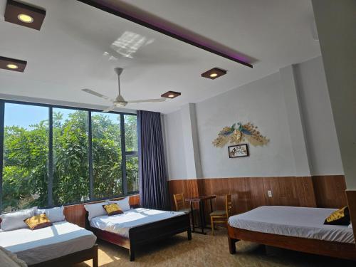 Cette chambre comprend deux lits, un canapé et une fenêtre. dans l'établissement Homstay Lynh Lynh Phú Yên, à Liên Trì (3)