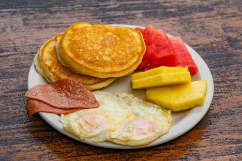 ein Teller Frühstücksspeisen mit Eiern und Obst in der Unterkunft Arenal Secret Gardens in Fortuna