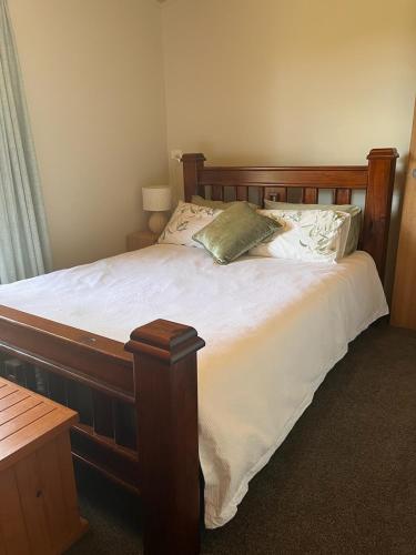 a bedroom with a large wooden bed with white sheets at Mountain Tranquility in Mount Tomah