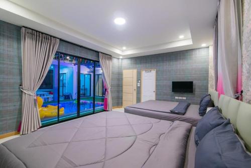 a bedroom with two beds and a large window at นาวาพูลวิลล่าหัวหิน VIP in Hua Hin