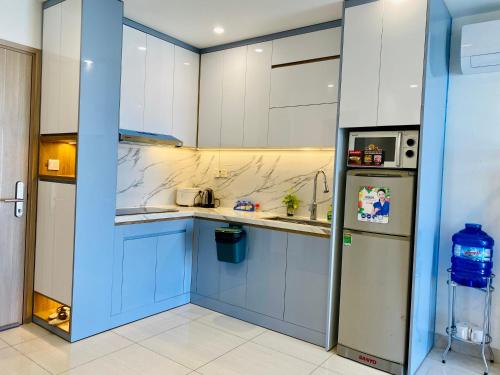 La cuisine est équipée de placards bleus et d'un réfrigérateur. dans l'établissement Vinhomes Grand Park Homestay, à Long Bình