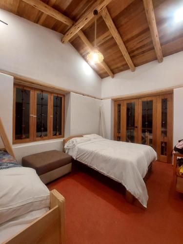 1 dormitorio con 2 camas en una habitación con techos de madera en Villa Maru, en Calca