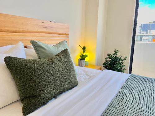 a bed with green and white pillows on it at Harbour Towers, Newcastle's Luxe Apartment Stays in Newcastle