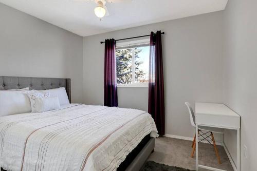 1 dormitorio con cama, escritorio y ventana en Bright and Spacious Home away from home, en Grande Prairie