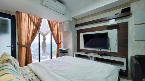 a bedroom with a bed and a tv and a window at Palam Mansion at Meisterstadt Pollux Habibie Apartment in Batam Center