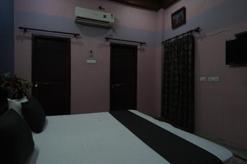 hotel banaras darbar في Kakarmatha: غرفة نوم فيها سرير بابين وتلفزيون