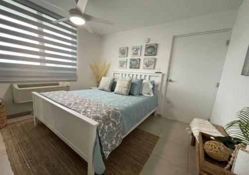 a bedroom with a bed with blue sheets and a window at Damaka 6 Guest BeachFront Pool Apt at Isabela, PR in Isabela